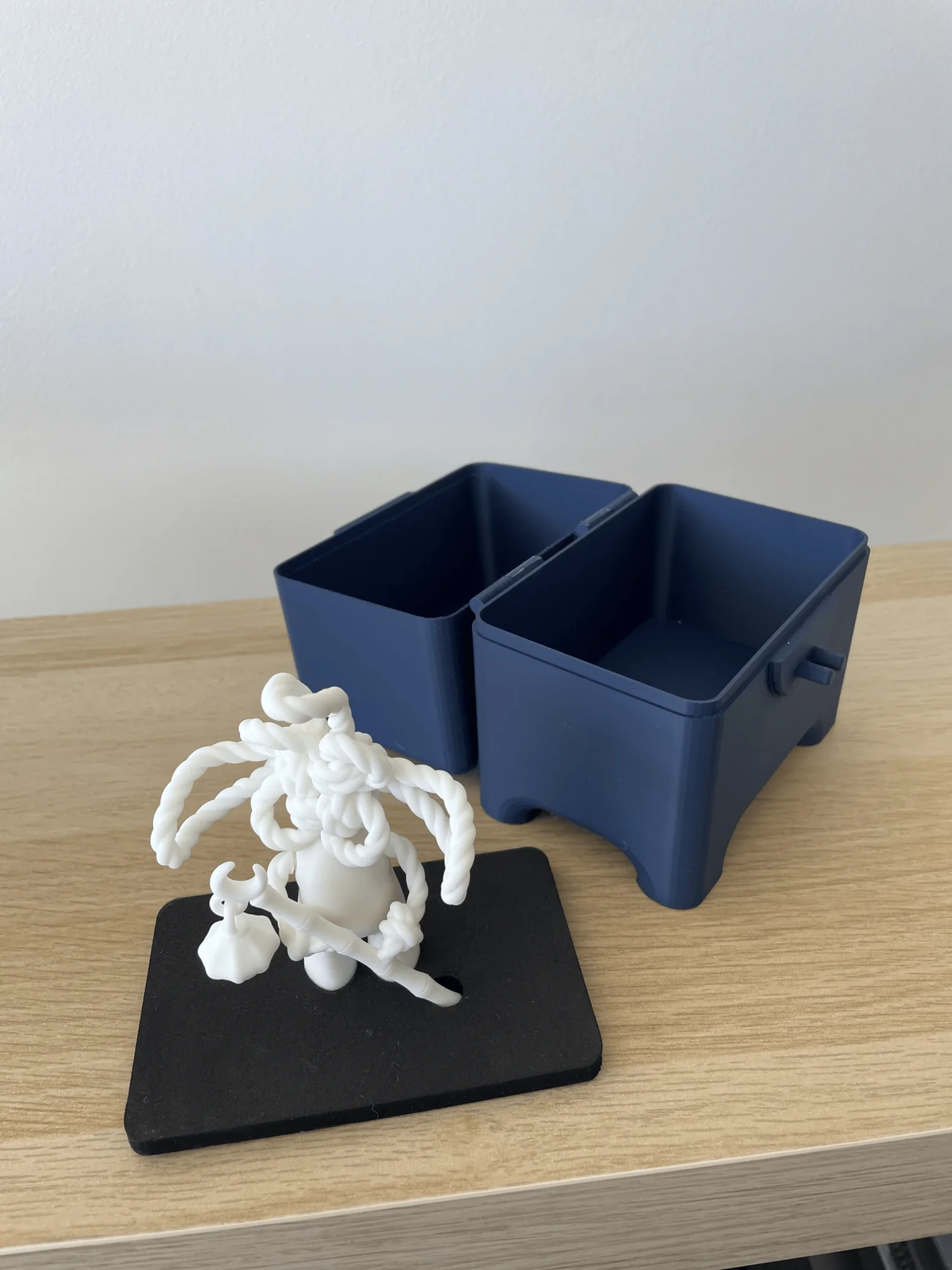 The navy box opened on its hinge beside a figurine standing on its black foam insert