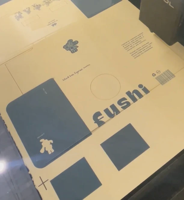 The outer packaging laser cut from watercolour paper, still on the cutter bed