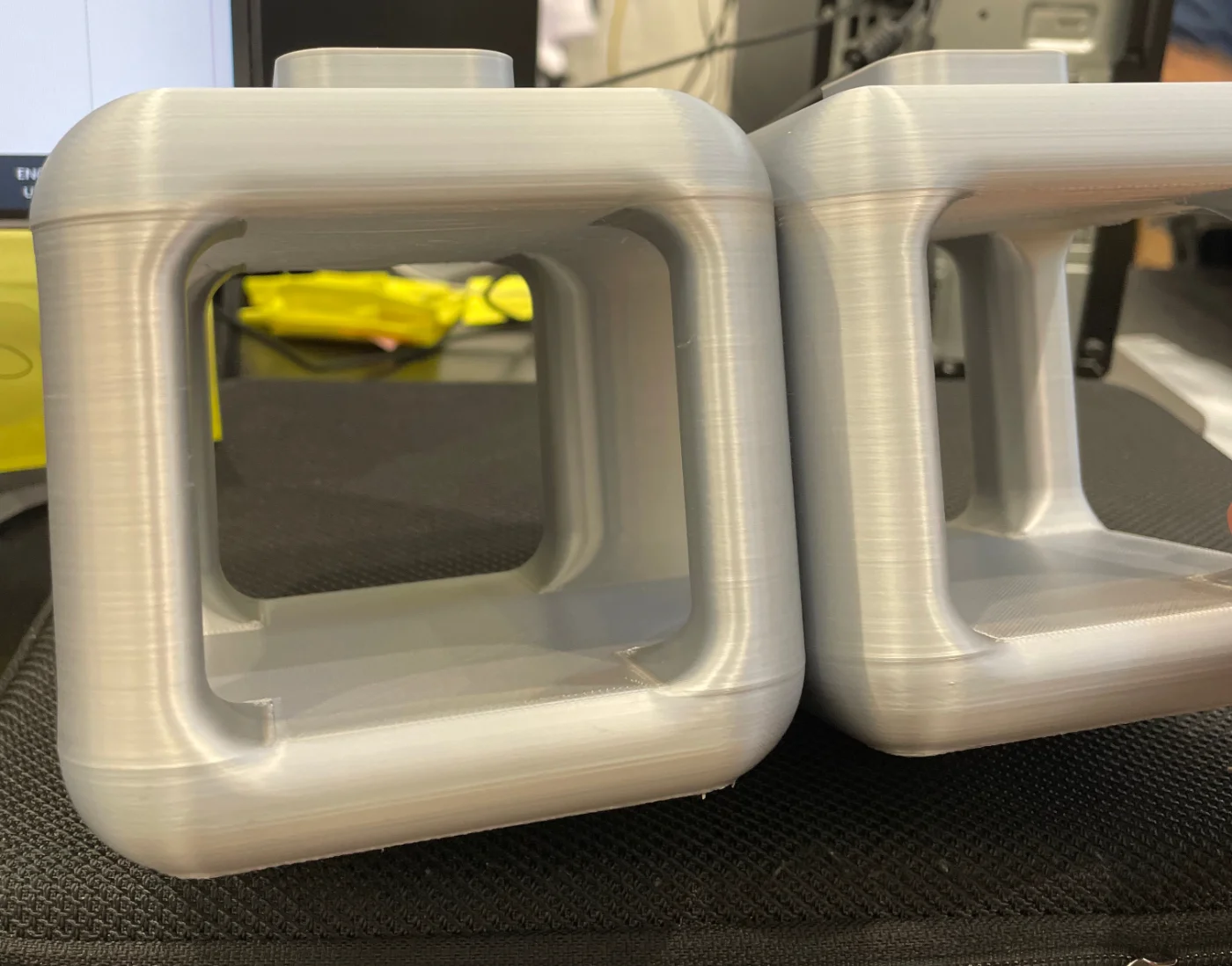 Two printed cube sections in grey PLA, with visible layer shift lines running across the columns